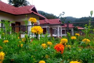 einen Garten mit gelben und orangefarbenen Blumen vor einem Haus in der Unterkunft Himani Heritage Resorts, formerly Camp Nishani Holidays in Madikeri