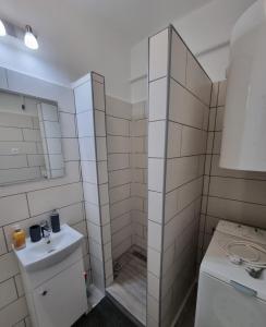 a white bathroom with a sink and a shower at Barcika Apartman in Kazincbarcika