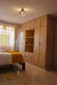 a bedroom with a bed and wooden cabinets at MORNINGSTAR 2BR APARTMENTS IN NAKURU in Nakuru