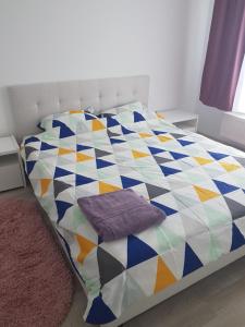 a bed with a colorful quilt on it in a room at Green apartament in Şelimbăr