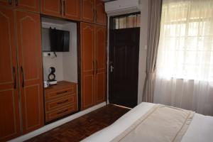 a bedroom with a bed and a tv and wooden cabinets at Cozy Stead in Nairobi