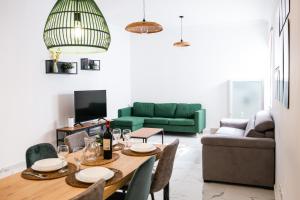 ein Wohnzimmer mit einem Tisch und einer grünen Couch in der Unterkunft Sliema 2BR Backyard Flat by Arco Collection in Sliema