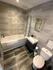 a bathroom with a toilet and a sink and a tub at Stylish City Centre Flat in Norwich