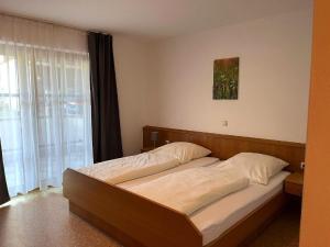 a bed in a bedroom with a large window at Landgasthof Blasini - Pfahlhof in Zandt