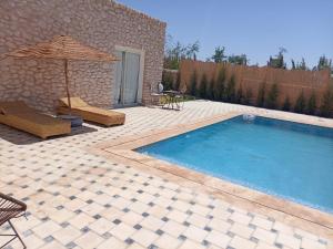 einen Pool mit einem Sonnenschirm, Stühlen und einem Tisch in der Unterkunft Oasis Villa Essaouira in Essaouira