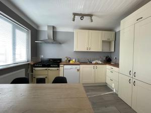 uma cozinha com armários brancos e uma mesa de cozinha em Lovely 2 bedrooms apartment West derby Liverpool em Deysbrook