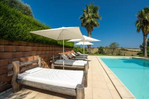 - une rangée de chaises longues avec parasols à côté de la piscine dans l'établissement Villa Iulia - VIBRA, à Controguerra