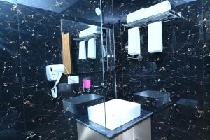 a black bathroom with a sink and a mirror at SPT Clarks Inn Suite, Mandi in Pāndoh