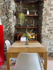 una mesa de madera con sillas blancas y un jarrón de flores en Apartament Cal Barracaire, en Vilallonga de Ter
