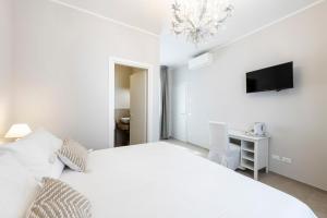 a white bedroom with a white bed and a tv at B&B De I Bravi in Cormano