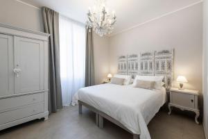 een slaapkamer met een wit bed en een kroonluchter bij B&B De I Bravi in Cormano