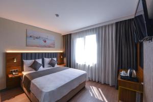 um quarto de hotel com uma cama grande e uma televisão em İSTPORT GARDEN HOTELS em Arnavutköy