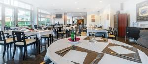 un restaurant avec des tables blanches, des chaises et des fenêtres dans l'établissement Hotel Air Penedès, à Vilafranca del Penedès