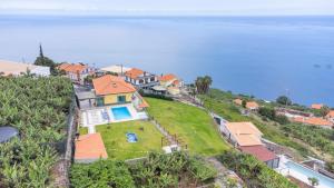 an aerial view of a house on a hill next to the ocean at Shell House by GALMI in Arco da Calheta