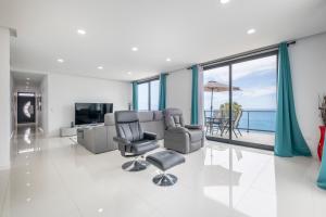 a living room with a couch and chairs and a television at Shell House by GALMI in Arco da Calheta