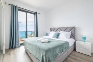 a bedroom with a bed and a large window at Shell House by GALMI in Arco da Calheta +28 photos