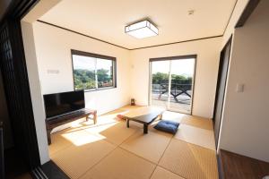 ein Wohnzimmer mit einem TV und einem Tisch in der Unterkunft トワイライトヒルズ Twilight Hills in Motobu