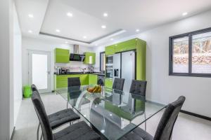a glass table in a kitchen with green cabinets at Shell House by GALMI in Arco da Calheta