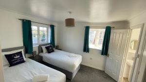 a small room with two beds and blue curtains at Stylish 4beds home, perfect for Company contractors and family stays - NEC, Airport, HS2, Resort World in Marston Green