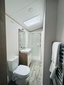 a white bathroom with a toilet and a sink at Hideaway Retreat with Hot Tub in York +8 photos