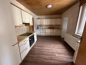 cocina con armarios blancos y suelo de madera en Ferienwohnung Darwin, en Ludwigshafen am Rhein