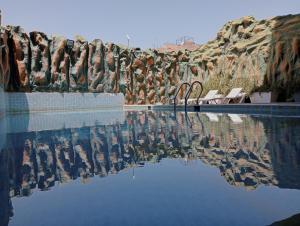 Hotel Gomassine في مراكش: تجمع مياه مع كراسي وجدار صخري
