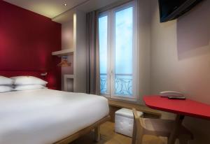sypialnia z łóżkiem, czerwonym biurkiem i oknem w obiekcie Hotel Andréa w Paryżu