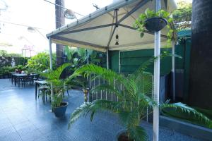 a patio with plants and an umbrella and tables at Hotel Saj Luciya in Trivandrum +13 photos