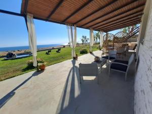 um pátio com cadeiras e uma mesa e vista para o oceano em MELENIOS HOUSES em Samotrácia