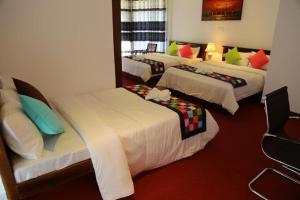 Habitación de hotel con 4 camas y almohadas coloridas en The Rosedale Grand Bungalow Nuwara Eliya en Nuwara Eliya