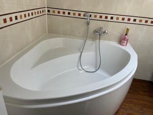 a white bath tub with a shower in a bathroom at Le Clos du Bas Courtil Guesthouse Omaha Beach in Osmanville