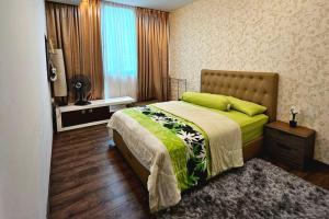 een slaapkamer met een bed met een groene deken en een raam bij The Cozy Homestay @ Jazz Suite Vivacity Kuching in Kampong Tabuan