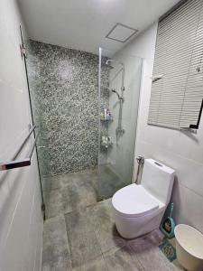 een badkamer met een toilet en een glazen douche bij The Cozy Homestay @ Jazz Suite Vivacity Kuching in Kampong Tabuan