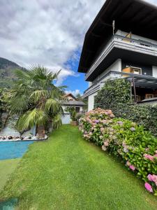 ein Haus mit einem Garten mit Blumen und einem Pool in der Unterkunft Pension Lärchenhof in Döbriach