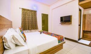 een slaapkamer met een bed en een flatscreen-tv bij FabHotel Radha Residency in Pondicherry