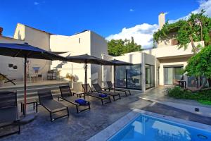 a patio with chairs and umbrellas next to a pool at Casa Cafenio by PosarelliVillas in Nípos