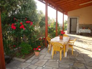 a patio with a table and chairs and red flowers at Filaktos Studios in Skala Sotiros