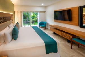 a bedroom with a large bed with a desk and a tv at Viva Azteca by Wyndham, A Trademark All Inclusive Resort in Playa del Carmen