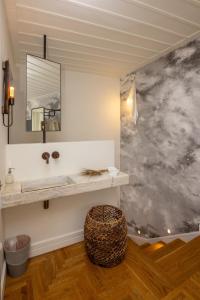 een badkamer met een wastafel en een spiegel aan een muur bij Elayio Old Town in Tinos Town