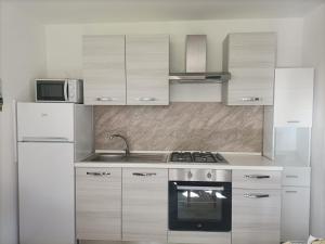 a white kitchen with a stove and a microwave at Pinzolocasa in Pinzolo