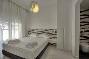 a white bedroom with a bed and a chandelier at Casa Cafenio by PosarelliVillas in Nípos +13 photos