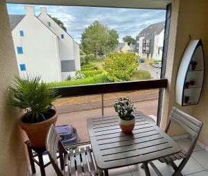 ein Tisch und Stühle auf einem Balkon mit Fenster in der Unterkunft Une pause à Bénodet in Bénodet