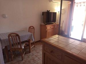 a kitchen with a table and a television and a table and chairs at Appartement avec piscine in Cavalaire-sur-Mer