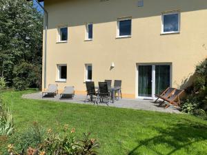 un patio con sillas y una mesa frente a un edificio en Ferienwohnung Familie Eder en Schönberg