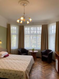 a hotel room with a bed and chairs and windows at Green Villa in Pärnu