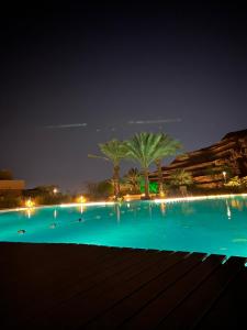 una gran piscina con palmeras por la noche en Al Raha chalet -al raha village -marsa zayed - قرية الراحة العقبة -مرسى زايد, en Áqaba