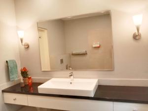 Luxre Homes - Villa in Koramangala في بانغالور: حمام مع حوض أبيض ومرآة كبيرة