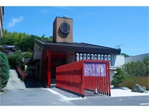 una valla roja frente a un edificio con reloj en The Ryokan Tokyo Yugawara - Vacation STAY 21489v en Miyakami
