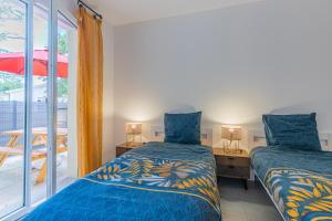 two beds in a room with a window at La p'tite maison de Charlotte in Cissac-Médoc