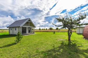 een klein huis in een veld met een boom bij Liepmalas - jaukus namukas Latvijos pajūryje in Nida